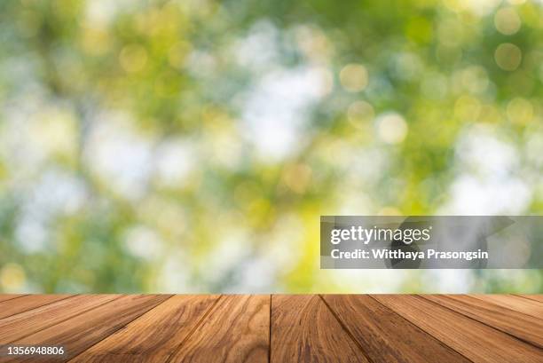 backgrounds: empty wooden table with defocused green lush foliage at background - ピクニ��ックテーブル ストックフォトと画像