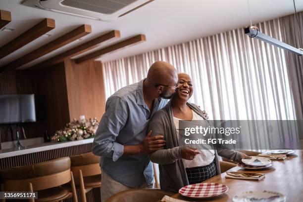 mature couple setting the table for lunch or dinner at home - generation x stock pictures, royalty-free photos & images