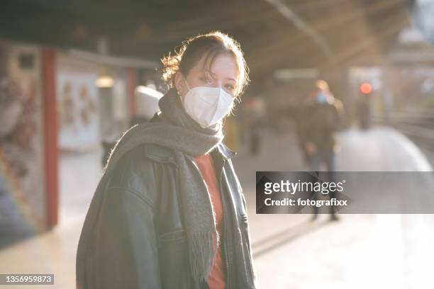 mädchen im teenageralter mit maske, das auf einem bahnsteig des bahnhofs steht - pollution mask stock-fotos und bilder