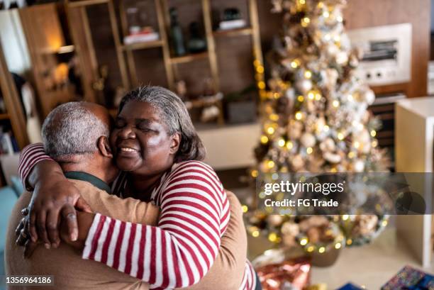 senior couple hugging each other at home - good news stock pictures, royalty-free photos & images