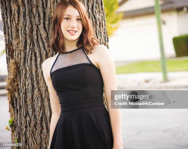 beautiful female teenager in her homecoming dress leaning on a tree - girl black dress stock pictures, royalty-free photos & images