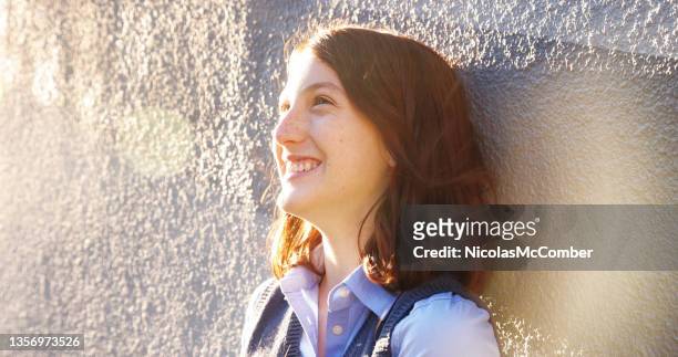 female teenager having a laugh photographed in profile with lens flare - portrait lens flare stock pictures, royalty-free photos & images