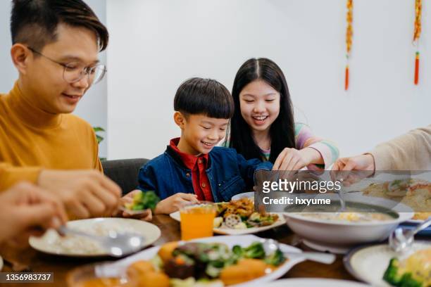 young sibling eating chinese new year family reunion dinner at home - asian food stock pictures, royalty-free photos & images