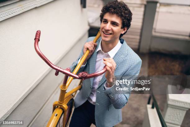 young businessman, with a cool attitude, using bicycle as a sustainable mode of transport - carrying bike stock pictures, royalty-free photos & images