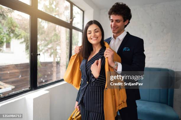 caucasian gentlemen helping to elegnat woman to dress her jacket - bem vestido imagens e fotografias de stock