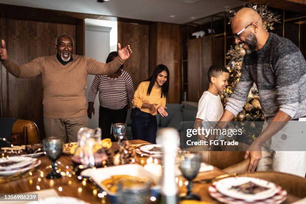 glückliche familie zusammen zum weihnachtsessen oder abendessen zu hause - african american christmas images stock-fotos und bilder