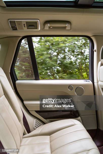 side view of luxury car interior with window open and blurred trees. - passagerarsäte bildbanksfoton och bilder