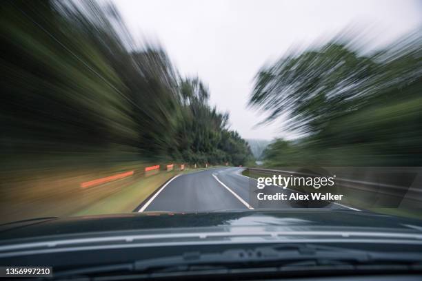 driving along a curved rural country road through forest with motion blur - driving car front view stock pictures, royalty-free photos & images