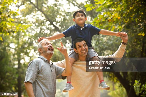 three generation family having fun at park - grandpa son stock pictures, royalty-free photos & images