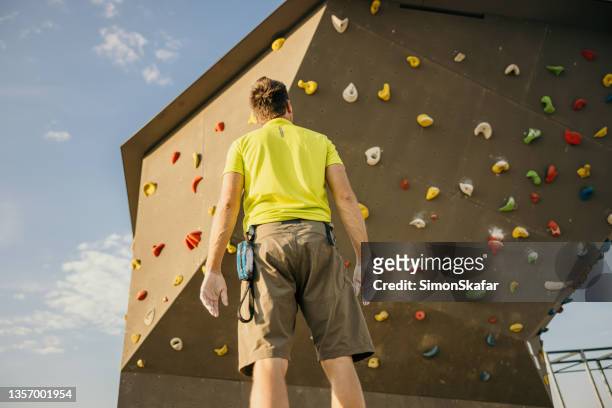 low angle view of a climber man looking at a outdoor bouldering wall - clambering imagens e fotografias de stock