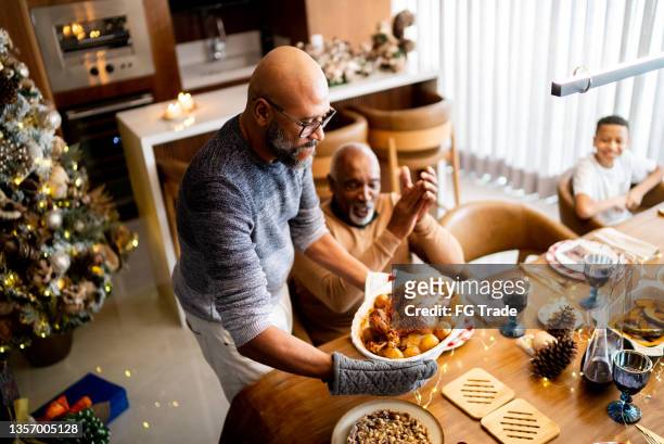 mature man serving roast turkey on christmas day at home - serving dish imagens e fotografias de stock
