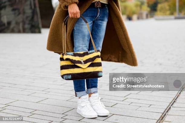 Yellow black striped fake fur bag by Saint Laurent and white sneakers by Celine as a detail of Influencer Gitta Banko, during a streetstyle shooting...