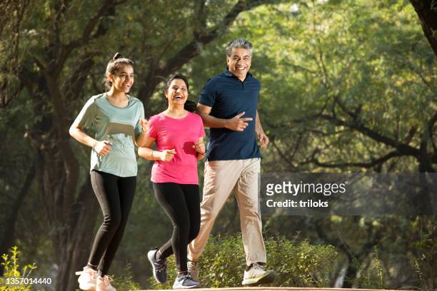 happy family jogging at park - indian family in their 40's with kids imagens e fotografias de stock