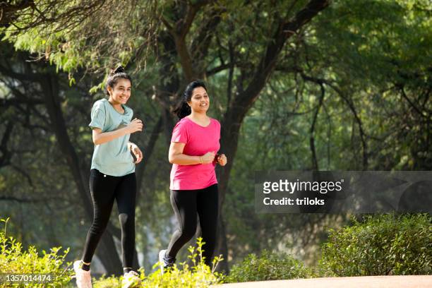 mother and daughter jogging at park - jogging stock pictures, royalty-free photos & images