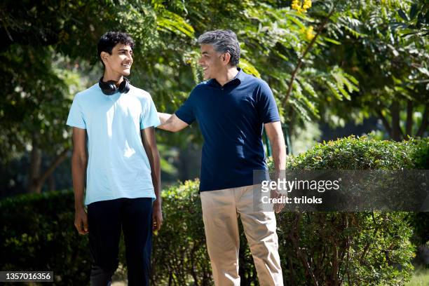unbeschwerter vater mit sohn im teenageralter verbringt freizeit im park - father and son discussion stock-fotos und bilder