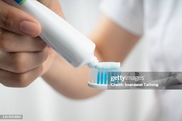 female squeezes toothpaste on the toothbrush - zahnpasta stock-fotos und bilder