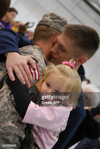 Iowa National Guarsman James Hauswirth hugs a relative as his daughter clings to his arm at a welcome home ceremony at facility in Davenport, Iowa...