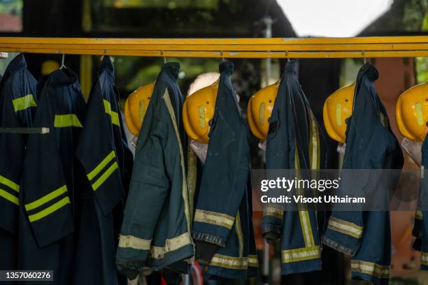 firefighter protection clothes hanging in the fire station. - firefighter foto e immagini stock