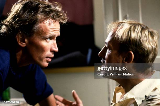 American film and stage actor Peter Weller talks with American actor Frederic Forrest as they film a scene during the 1989 drama film "Cat Chaser"...