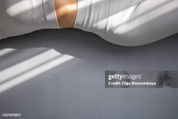 a beautiful woman's thin waist in sports clothes lies on a gray rug, copy space - yoga rug photos et images de collection