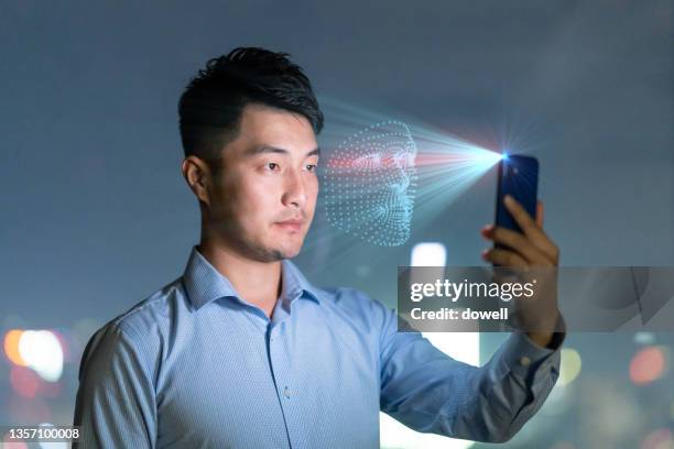 young man using facial recognition technology with mobile phone - facial recognition technology stock pictures, royalty-free photos & images