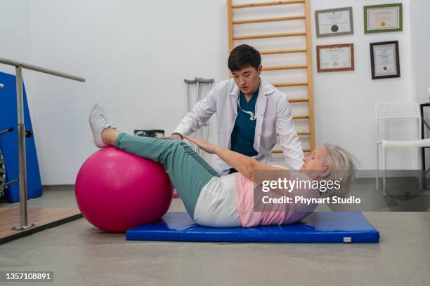 senior woman with trainer doing rehab using pilates ball in the rehabilitation center - yoga ball work 個照片及圖片檔