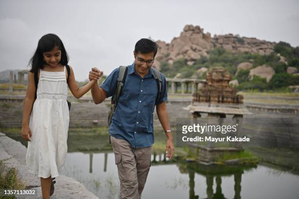 father and daughter walking on the steps of old ruins of a step tank, hampi, karnataka - stepwell india stock pictures, royalty-free photos & images
