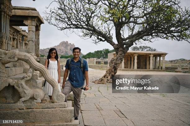 father and daughter standing in an ancient stone temple - south indian temple stock pictures, royalty-free photos & images