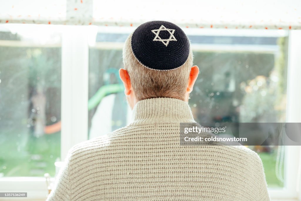 Jewish man wearing skull cap at home