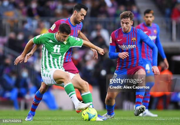 Guido Rodriguez of Real Betis is challenged by Sergio Busquets and Nico Gonzalez of FC Barcelona during the La Liga Santander match between FC...