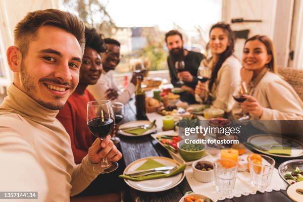 selektive fokusaufnahme von freunden, die während des thanksgiving-mittagessens selfies machen - table dinner winter stock-fotos und bilder