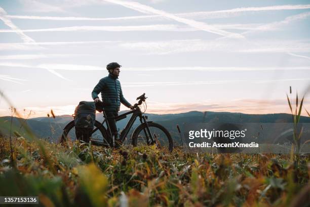 e-mountainbiker entspannt auf wiese, bei sonnenaufgang - bycicle stock-fotos und bilder
