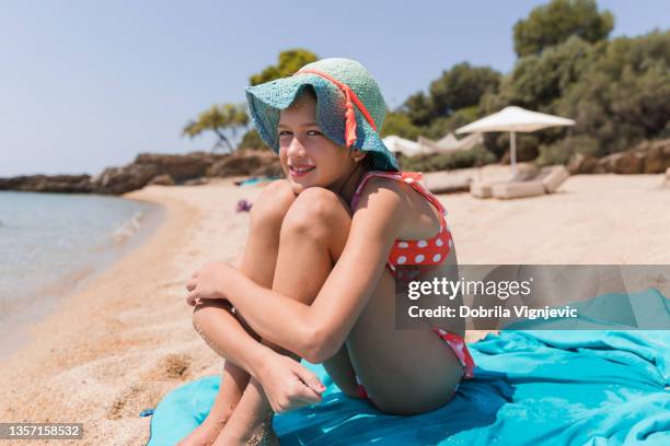 fille embrassant les genoux sur la plage et souriant - ado en maillot de bain photos et images de collection