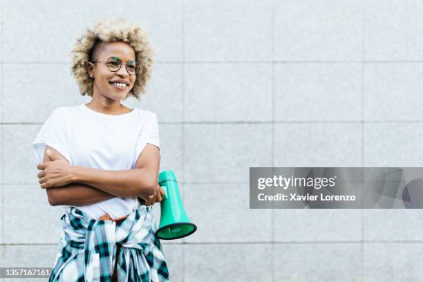 african american woman holding a megaphone by wall - aktivist stock-fotos und bilder