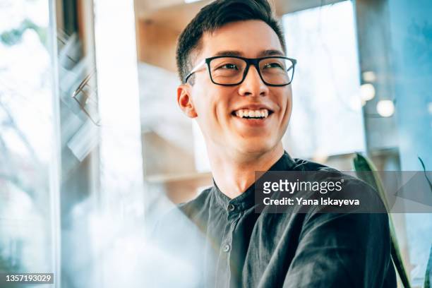 portrait of a young handsome asian entrepreneur, smiling and looking forward to the future innovations - erwartung stock-fotos und bilder