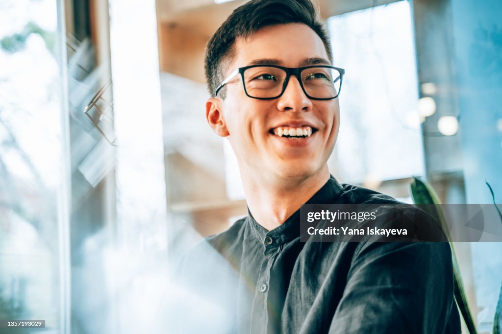 Portrait of a young handsome Asian entrepreneur, smiling and looking forward to the future innovations