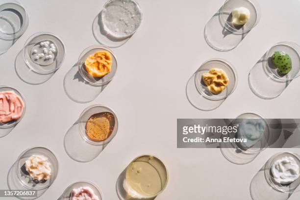 background made with different beauty products in many petri dishes. face serums, gel, scrubs, tonic with pearls and a lot of multicolored creams. concept of cosmetics laboratory researches. photography in flat lay style - 製品　実験 ストックフォトと画像