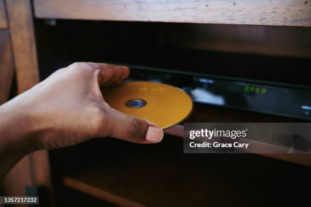woman puts disk into dvd player - dvd speler stockfoto's en -beelden