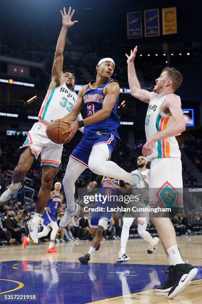 Jordan Poole of the Golden State Warriors looks to make a play with the ball against Tre Jones and Jakob Poeltl of the San Antonio Spurs in the third...