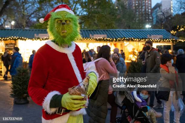 Child looks back at a person dressed in a Grinch costume holding a bottle of Modelo beer at the Union Square Holiday Market on December 04, 2021 in...