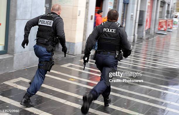 Police run with unholstered guns after a grenade attack at Place St-Lambert in the heart of the city on December 13, 2011 in Liege, Belgium. Two...