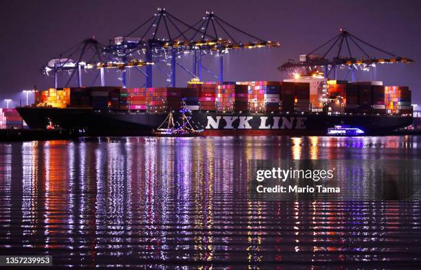 Holiday themed boats parade past a container ship loaded with shipping containers at the Port of Los Angeles during the ‘Los Angeles Harbor Holiday...
