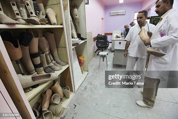 Technicians stand next to prosthetics at the Factory of Prosthetic Limbs on December 13, 2011 in Baghdad, Iraq. Wounded Iraqis face a shortage of the...