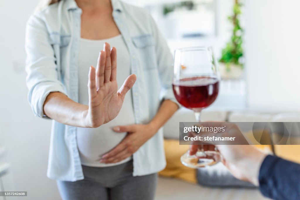 Pregnant woman refusing a glass of wine. Alcohol In Pregnancy. Unrecognizable Expectant Lady Gestring Stop To Offered Glass Of Wine