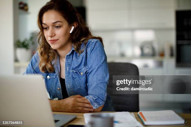 mujer joven con auriculares bluetooth con videoconferencia en casa - conocer fotografías e imágenes de stock