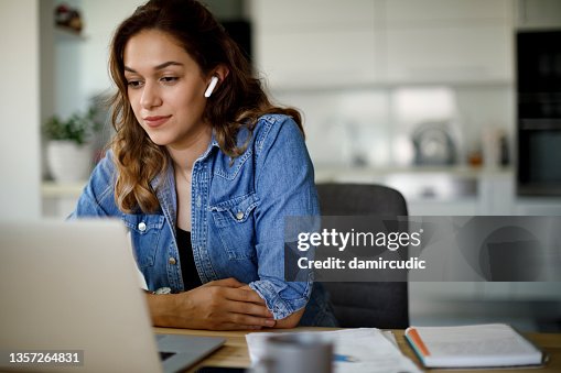 Jovem com fones de ouvido bluetooth tem videoconferência em casa Jovem com fones de ouvido bluetooth tem videoconferência em casa