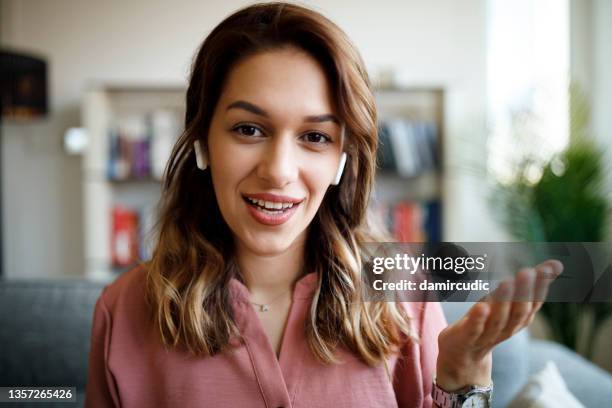 young smiling woman with bluetooth headphones having video call at home - professional digital video camera stock pictures, royalty-free photos & images