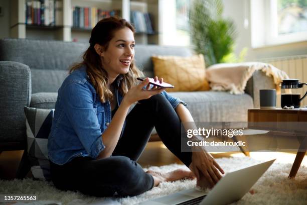 mujer joven que usa el teléfono móvil para trabajar en casa - reconocimiento del habla fotografías e imágenes de stock