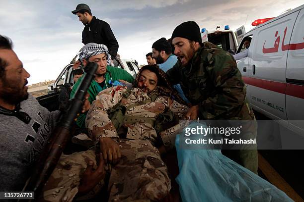 An injured rebel soldier against Col. Muammar Gaddafi is carried at the frontline March 9, 2011 near Ras Lanuf, Libya. The government military and...