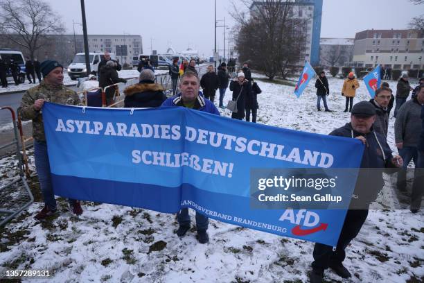 Supporters of the right-wing Alternative for Germany political party hold a banner that reads: "Stop asylum paradise Germany!" while marching near a...